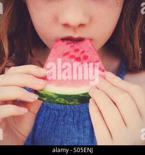 Close up of young girl with red hair eating a slice of watermelon Stock Photo