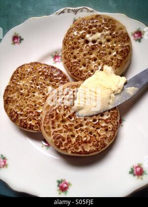Hot buttered crumpets on a pretty plate Stock Photo