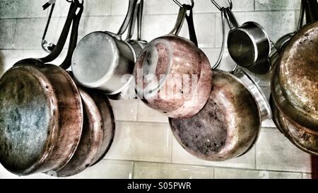 A set of well used saucepans hanging. Mobile phone photo with some phone or tablet post processing. Stock Photo
