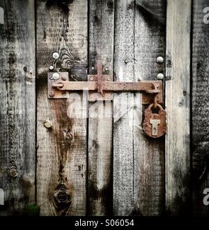 Rusty bolt and padlock on an old barn door Stock Photo