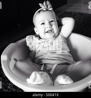 Little baby girl sitting in basket and laughing Stock Photo