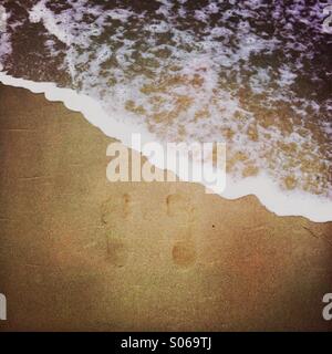 Footprints on the beach at the shoreline. Stock Photo