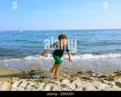 A little boy playing on a sunny beach during summer in Connecticut, USA. Stock Photo