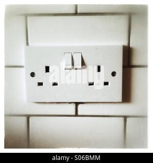 Double plug socket on a tiled wall Stock Photo