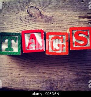 It's a photo of woodblocks toy with alphabet letters on them that are combined together to form the word TAGS Stock Photo
