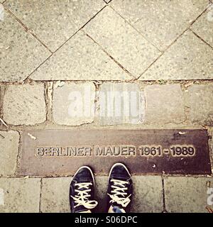 Berlin Wall memorial stones in pavement with feet Stock Photo