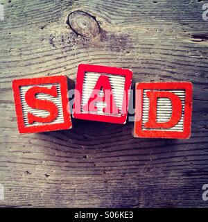 It's a photo of woodblocks toys will alphabet letter on them which are combines together to create the word SAD Stock Photo