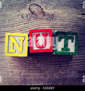 It's a photo of woodblocks toys will alphabet letter on them which are combines together to create the word NUT Stock Photo