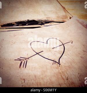 Love heart drawn onto dirty abandoned car covered in sand in parking lot in Dubai UAE Stock Photo