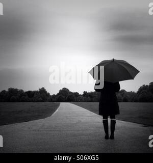 A women stands in Hyde Park on a rainy day. London, England UK. Stock Photo