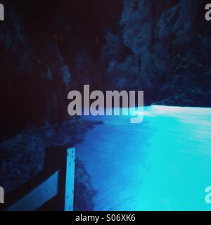 View at sea cave with blue reflection from boat Stock Photo