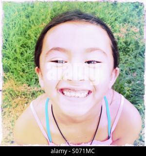 Close up portrait of a grinning seven-year-old Asian American girl. Stock Photo