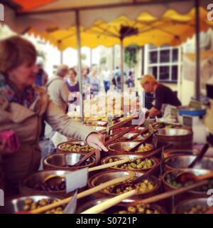 Choosing olives on a market stall at Stroud farmers market, Gloucestershire, UK Stock Photo