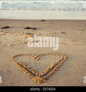 Heart shape drawn in sand on the beach Stock Photo