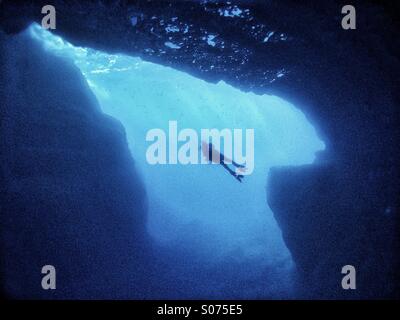 Mature male scuba diver swimming across underwater cavern Stock Photo