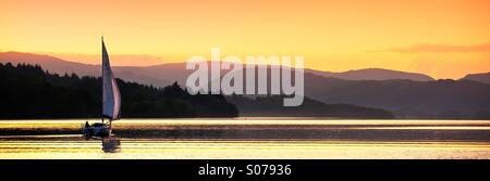 A yacht sailing at sunset on lake Windermere. Stock Photo