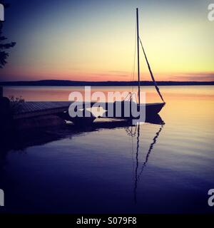 A small sailing boat moored for the night at a Finnish lake in Arctic midnight sunshine Stock Photo
