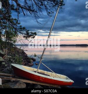 A boat drawn up on a mooring at a North Finland Nordic summerhouse lake in the Arctic Summer midnight sun Stock Photo