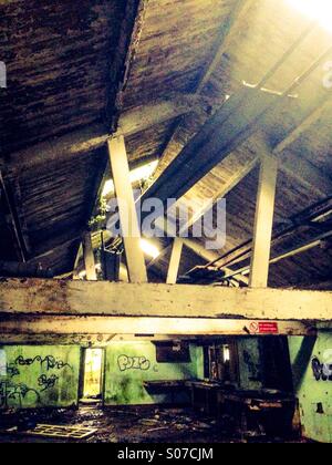 Old abandoned building with light streaming in through the broken roof Stock Photo