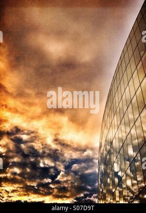 Reflections of clouds at dusk in windows of office building Stock Photo