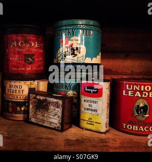 Several old tobacco tins and other items on a shelf in a long closed General Store in Tennessee. Stock Photo