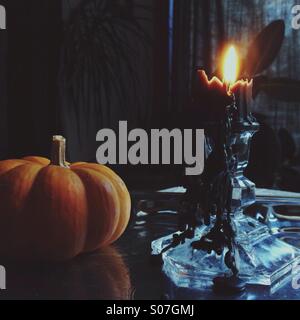 Halloween still life with black dripping candle and small pumpkin. Stock Photo
