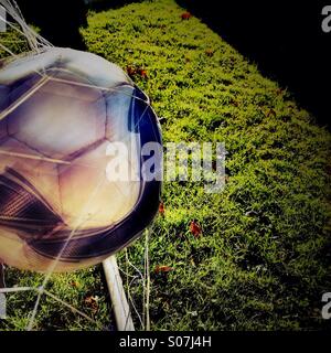 Blurred football hitting back of net Stock Photo