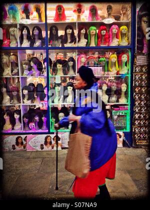 Elderly lady with walking stick walking past Hair shop at Leeds market, West Yorkshire, UK Stock Photo