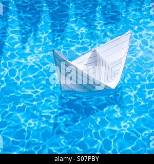 Paper boat in swimming pool. Stock Photo