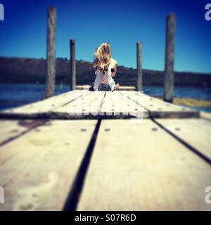 Young girl sitting on a jetty Stock Photo