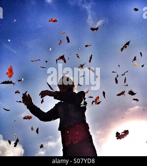 Young girl with autumn leaves falling around her Stock Photo