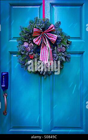 Unlock Christmas - a Christmas wreath hanging on a blue door in the snow Stock Photo