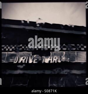 Neon sign for a fast food restaurant drive thru as seen through raindrops on a car windshield. Stock Photo