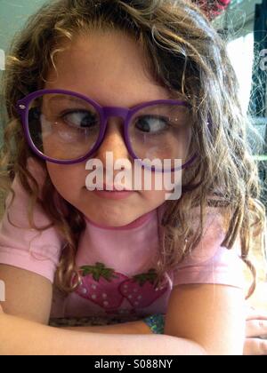 Young girl wearing big glasses and playing cross eyed. Stock Photo