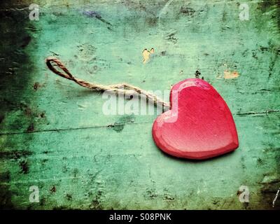 Red wooden heart with a thread on grungy background Stock Photo