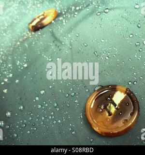 Closeup of water droplets and buttons on a dark green mackintosh Stock Photo