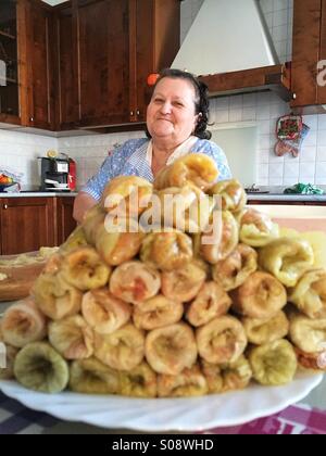 Grandmother in the kitchen with traditional romanian dish, sarmale, cabbage leaves stuffed with minced meat Stock Photo