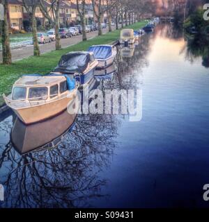 Boats are seen along a canal in a small, Dutch village. Stock Photo