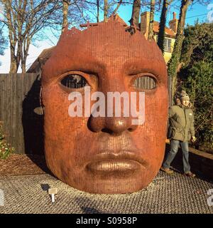 Man standing by the face sculpture outside the Marlowe Theatre Canterbury by the river Stour. Stock Photo