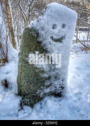 Smiley face drawn in a snow covered stone marker. Stock Photo