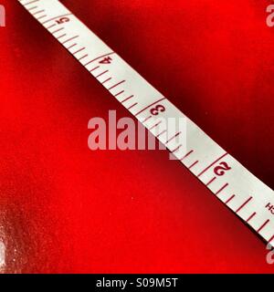 Tape measure showing inches on a red background Stock Photo