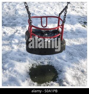 Child's swing in snow covered park Stock Photo