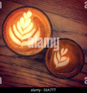 Large and small latte coffees together on wooden table seen from above Stock Photo