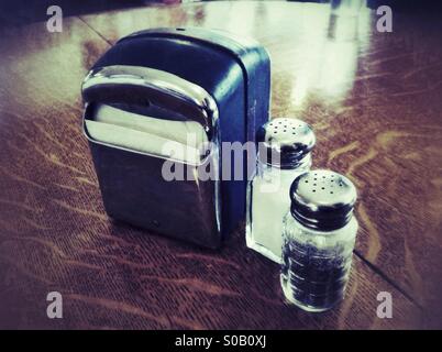 salt and paper shakers and box of tissues on a wooden table in the cafe Stock Photo