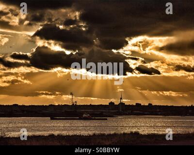 A ship sails up the river Thames at Rainham Marshes, Essex, UK during a spectacular sunset. Stock Photo