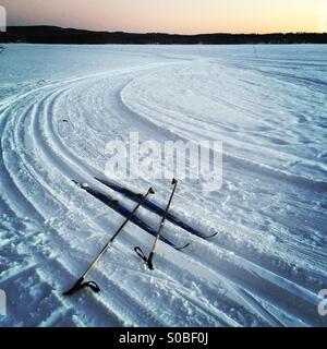 A pair of cross country skis and poles in the shape of a hashtag in some wilderness tracks on a frozen Nordic lake Stock Photo