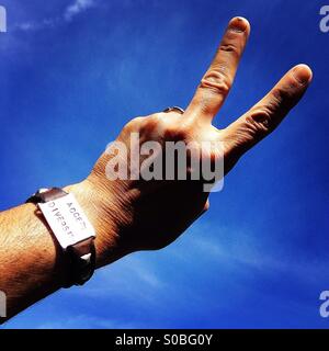 'Accept Diversity' leather and steel bracelet on man making two finger peace sign at sky Stock Photo