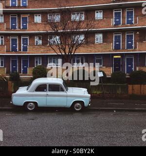 an old light blue car parked on the pavement in front of a block if flats in Eade rd, Hackney , London