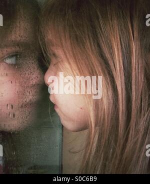 Girl pressing her nose against wet bathroom mirror Stock Photo