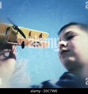 Looking up at a boy holding his model airplane Stock Photo